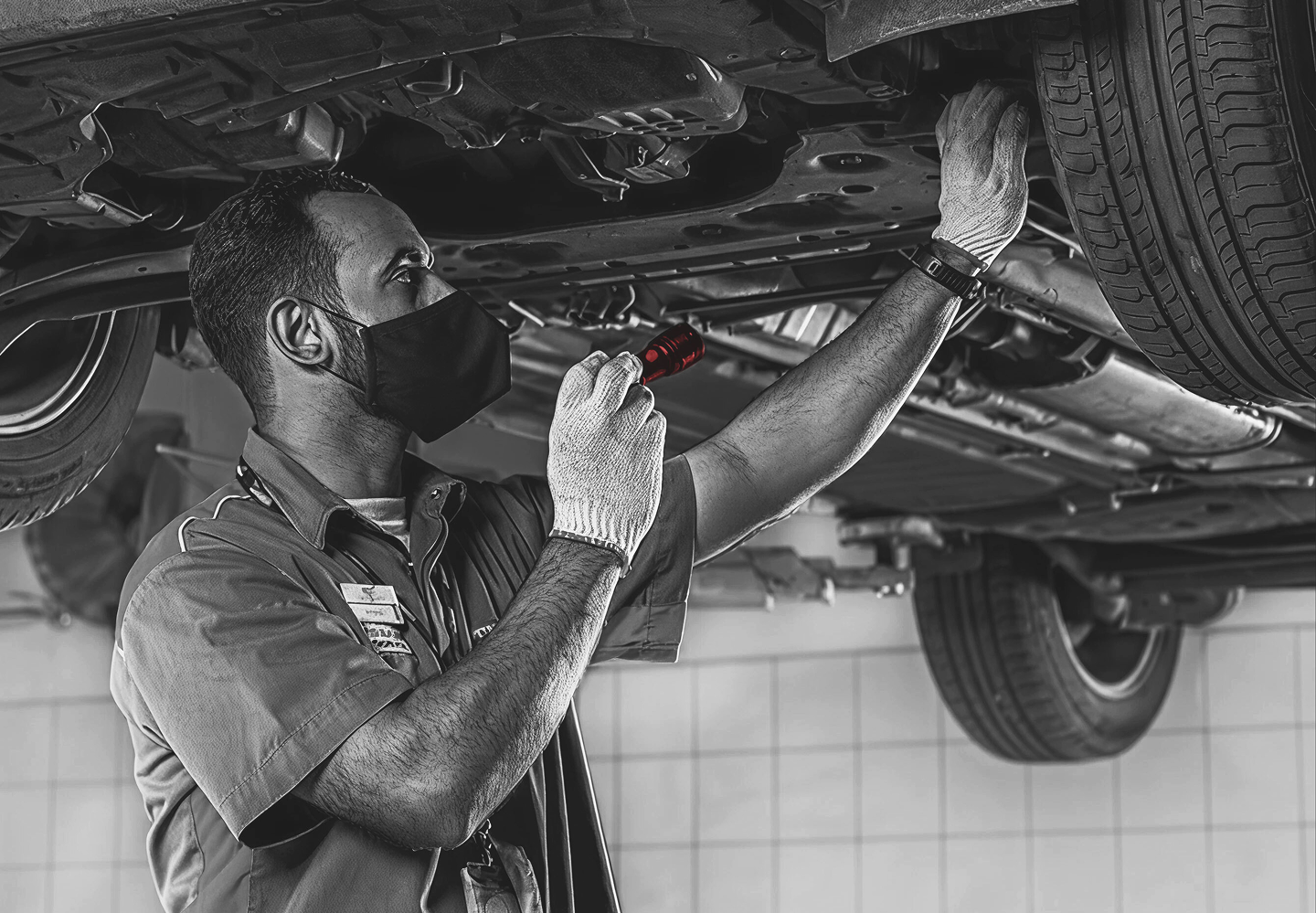 Technician working under a vehicle in a Petromin service bay