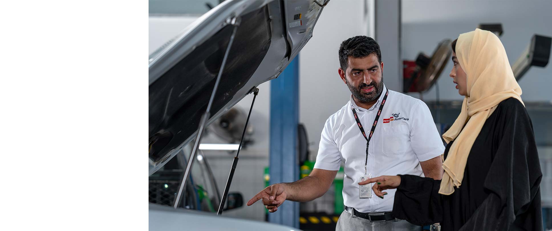 Petromin technician explaining vehicle components under the hood to a customer